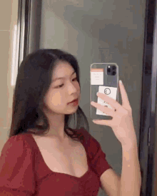 a young woman is taking a selfie in the mirror with her phone .