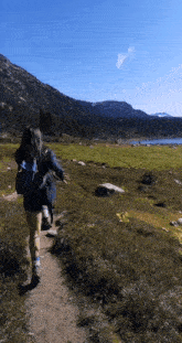 a woman with a backpack is walking down a path