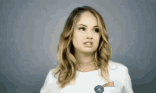 a woman wearing a white t-shirt with a comet on it is making a face .