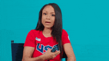 a woman wearing a red usa shirt holds a remote control
