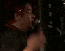 a man with red hair is singing into a microphone with his mouth open .