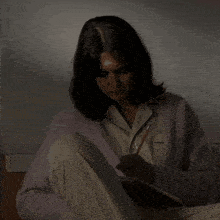 a woman sits on a bed writing in a notebook with a pen