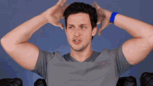 a man with his hands on his head wearing a grey shirt