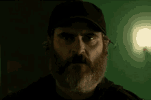 a close up of a man with a beard wearing a hat and looking at the camera .