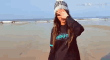 a woman in a hat and sunglasses is standing on a beach .