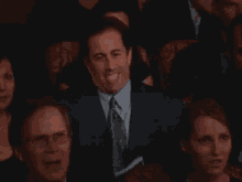 a man in a suit and tie is waving his hand in a crowd