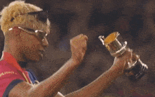 a man wearing sunglasses holds up a trophy