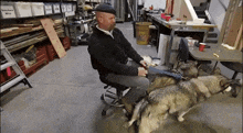 a man is sitting in a chair with two dogs in front of a shelf with boxes that say smokey wire