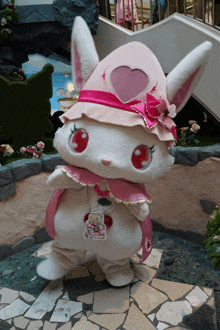 a stuffed animal wearing a pink cape and hat with a heart on it