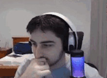 a man wearing headphones is sitting in front of a microphone and looking at the camera .