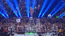 a wrestler stands on a ladder in a wrestling ring with a crowd behind him