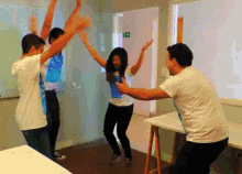 a group of people are dancing in a room with a green exit sign