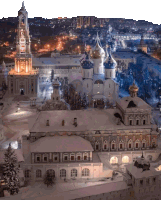 an aerial view of a snowy city at night with a clock tower in the foreground