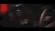 a man smoking a cigarette in a car with a red light behind him