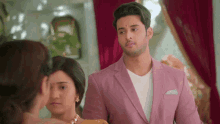 a man in a pink suit is looking at a woman
