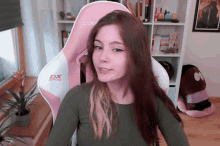 a girl is sitting in a pink and white dx gaming chair