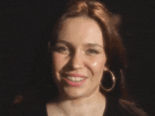 a close up of a woman wearing hoop earrings and smiling