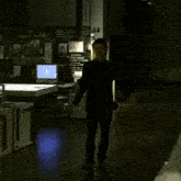 a man in a black suit is standing in a dark room looking at the camera .