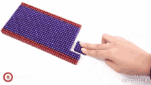 a person 's hand is touching a piece of purple and red beads made in animotica