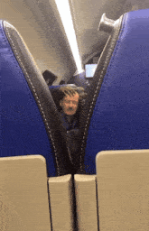 a man with glasses sits in a blue seat