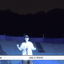 a man in a white t-shirt is dancing in a dark stadium