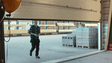 a man walking through a warehouse with a stack of bricks on the ground