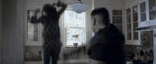 a man and woman are fighting in a kitchen