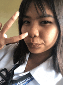 a girl giving a peace sign wearing a lanyard that says ' jador ' on it