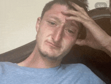 a man sitting in a chair with his hand on his forehead and the date 5/20 on the bottom right