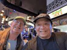 a man and woman are posing for a picture in front of a salad jack 's restaurant