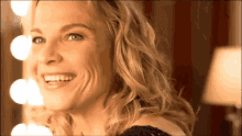 a woman smiles in front of a mirror with lights on