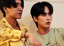 two young men are standing next to each other and one of them is wearing a green shirt that says woah
