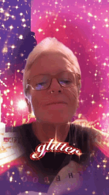 a woman wearing glasses and a black shirt with the word glitter on it