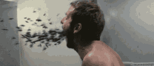 a man with a beard is throwing up a bunch of bugs in his mouth .