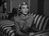 a woman is sitting on a striped couch looking at something