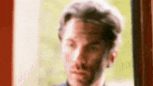 a close up of a man 's face looking out of a window