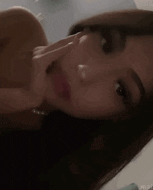 a close up of a woman 's face with a hand on her chin .