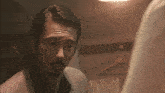 a man with a beard looks at his reflection in a mirror