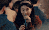 a woman is drinking a drink through a straw while sitting at a table with other people .