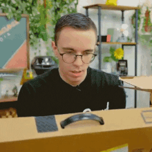 a man wearing glasses is looking at a cardboard box