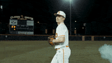 a baseball player stands in front of a scoreboard that says claude m smith field