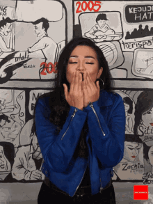a woman blowing a kiss in front of a wall with drawings and the year 2005