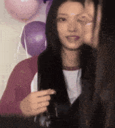 a woman in a pink sweater is talking to another woman in front of balloons