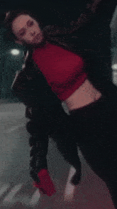 a woman wearing a red crop top and black pants
