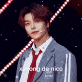 a young man in a suit and tie is standing in front of a microphone and says xinlong de nico