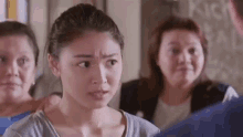 a woman is making a funny face while standing next to two other women in a room .