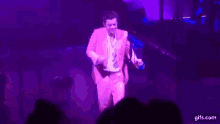 a man in a pink suit is standing on a stage in front of a microphone .