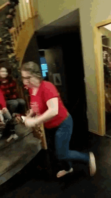 a woman in a red shirt is holding a wii remote