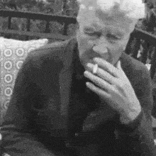 a man is smoking a cigarette in a black and white photo .