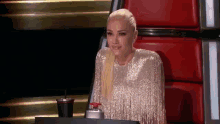 a woman in a sequined dress is sitting in a chair with a drink in her hand .